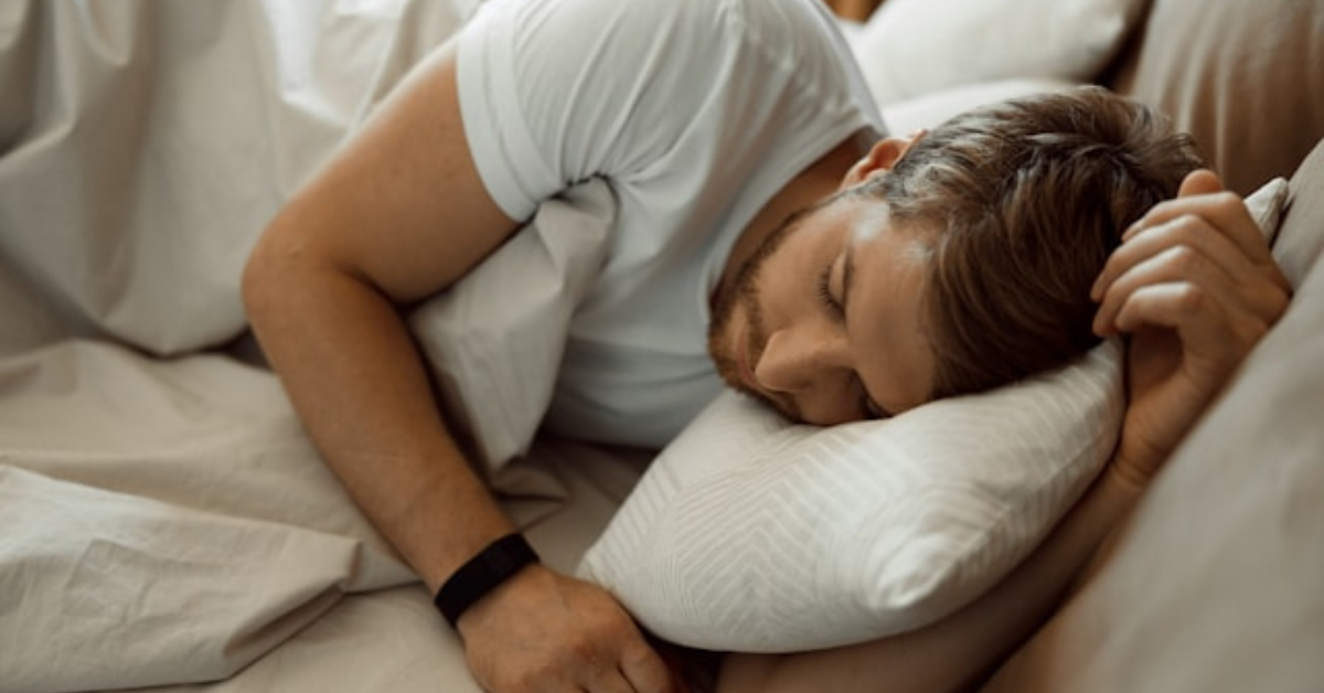 Man peacefully sleeping in a cozy bedroom, highlighting the importance of prioritizing sleep to reduce stress and improve overall health.