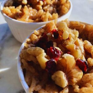 A creamy bowl of jasmine rice pudding topped with walnuts and dried cranberries.