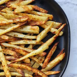 Healthy, homemade oven-baked french fries perfectly seasoned and featured on a plate.