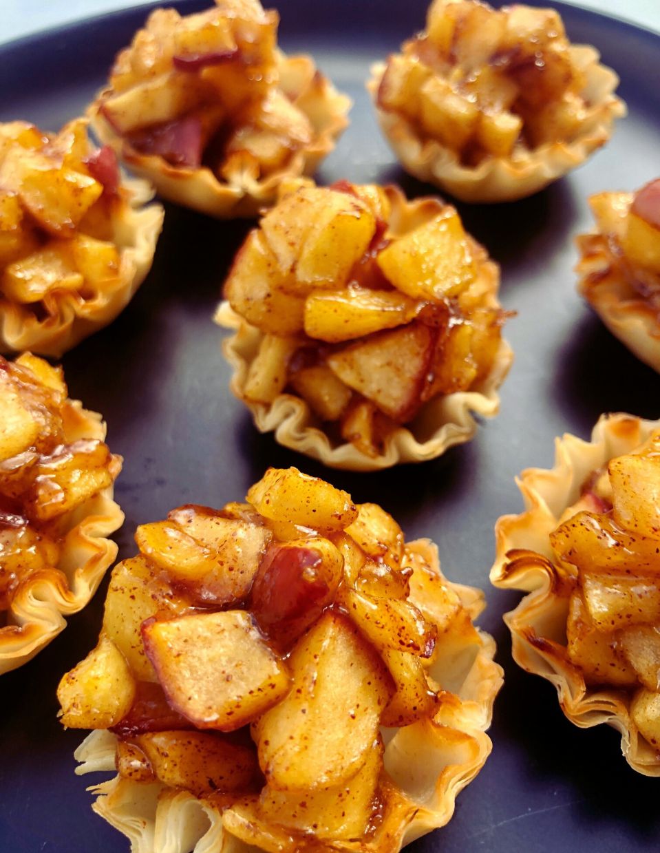 A plate of flaky phyllo cups filled with apple pie filling, ready to serve as a healthy dessert.