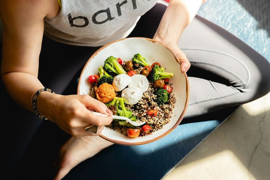 A woman with PCOS eating a colorful quinoa salad with beans and vegetables, a healthy meal for managing insulin resistance and weight loss.