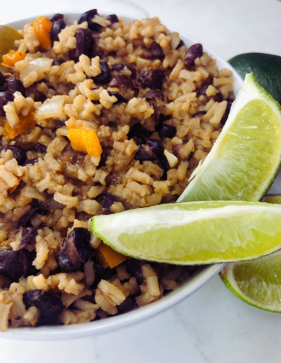 A plate of Cuban black beans served over white rice, garnished with fresh cilantro and lime wedges for a vibrant and nutritious meal.