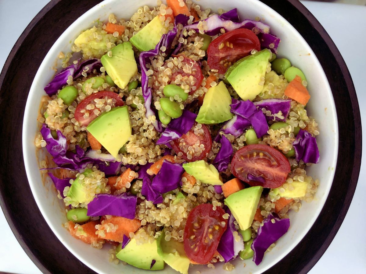 High-fiber quinoa bowl topped with edamame, vibrant red cabbage, creamy avocado, and fresh onions, a nutritious and colorful meal for supporting digestive health.