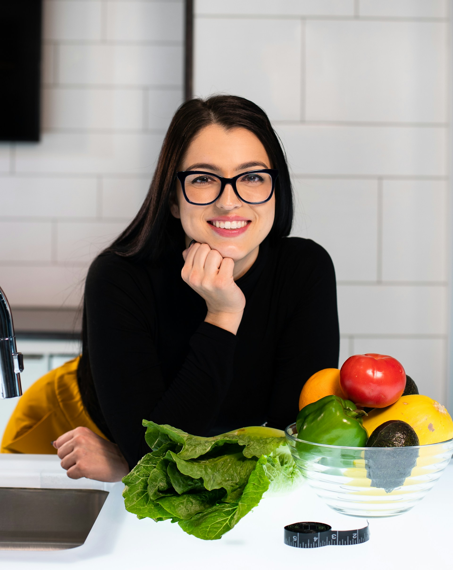 Registered Dietitian Nutritionist in kitchen with functional foods like leafy greens, apples, and avocados in a glass bowl