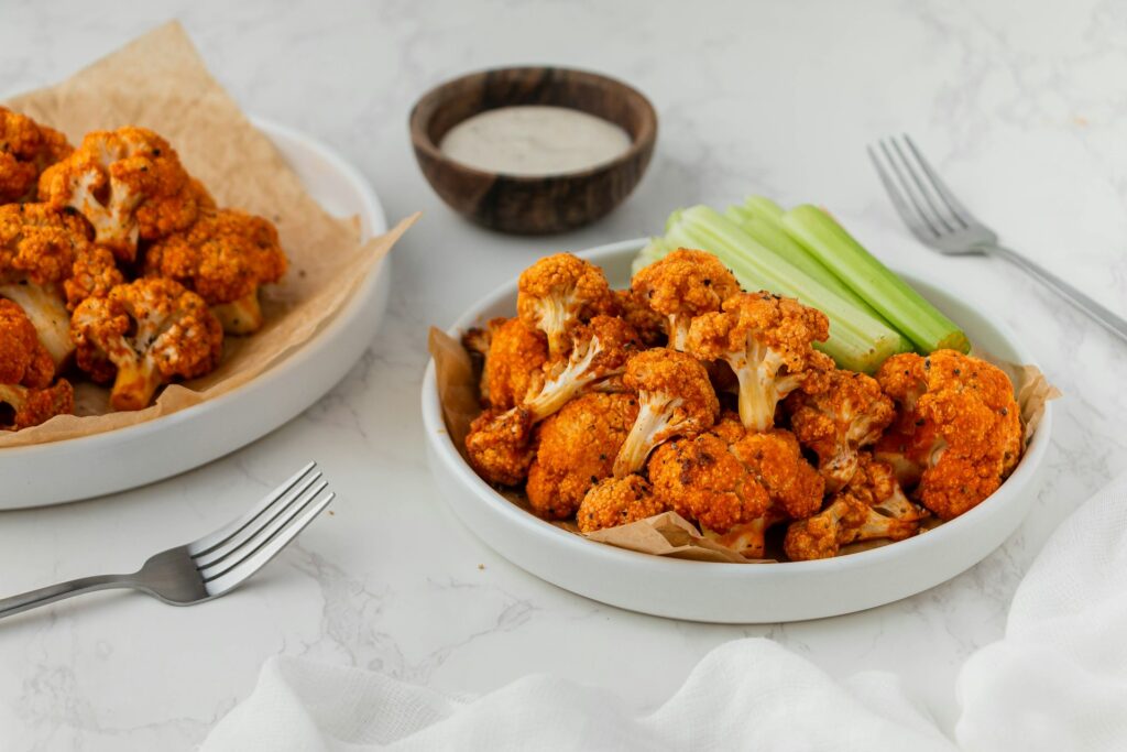 Buffalo cauliflower wings, a healthy plant-based snack option rich in fiber and nutrients, served with ranch dipping sauce.