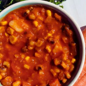 Warm and hearty vegetable soup served in a white bowl, filled with colorful vegetables like carrots, peas, and beans, in a rich tomato-based broth.