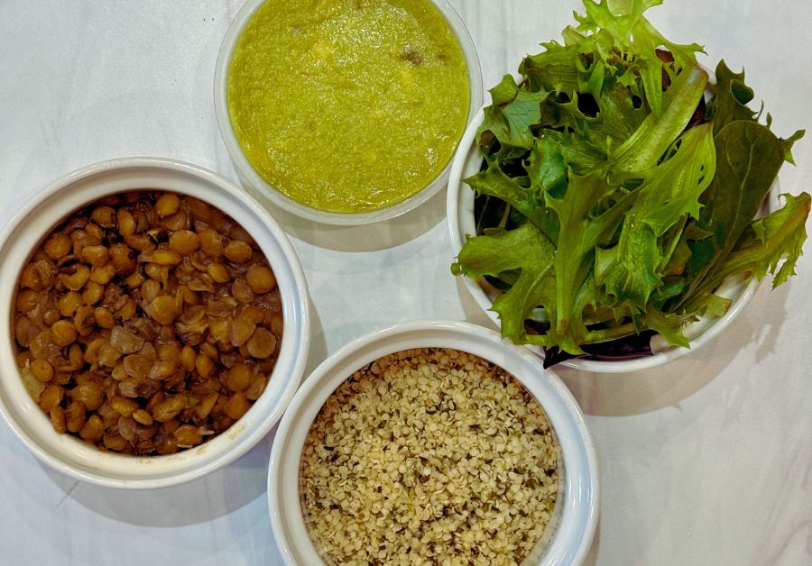 Store bought spicy guacamole, spring mix, cooked green lentils, and hemp seeds, ingredients for making avocado toast.