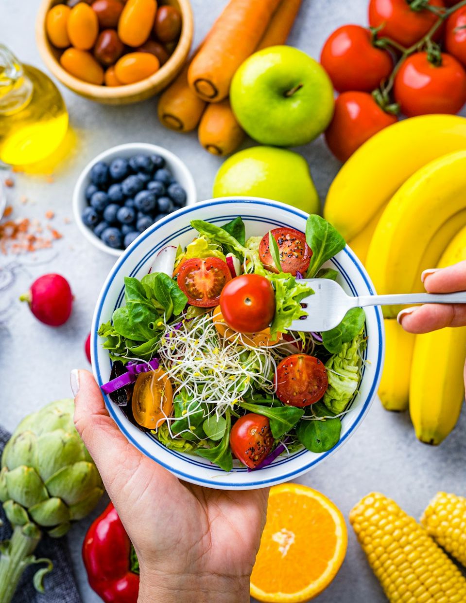 A vibrant salad topped with fresh sprouts, set against a background of colorful fruits on a table. The image symbolizes nutrient-dense food choices, nutrition counseling, and the promotion of healthy eating through personalized dietary guidance.