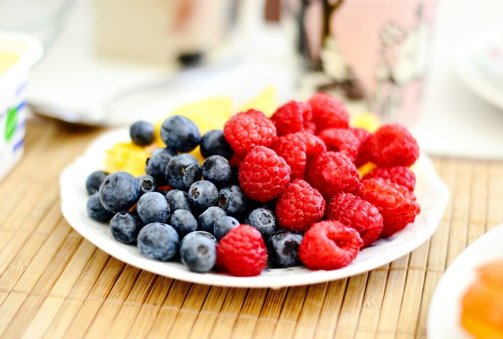 A plate of colorful blueberries and raspberries rich in antioxidants to boost immune health to keep you from getting sick. 