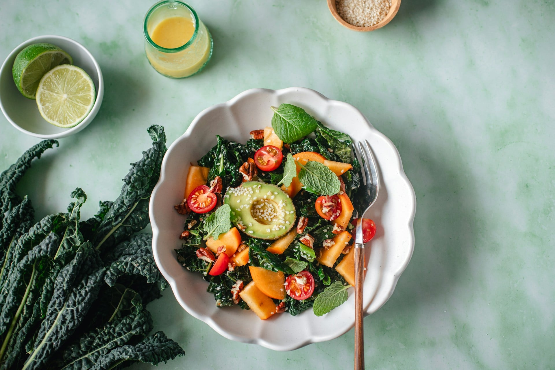 A vibrant plant-based salad with kale, avocado, cherry tomatoes, persimmons, and fresh herbs, highlighting the benefits of plant-based diets for kidney disease management and overall kidney health.