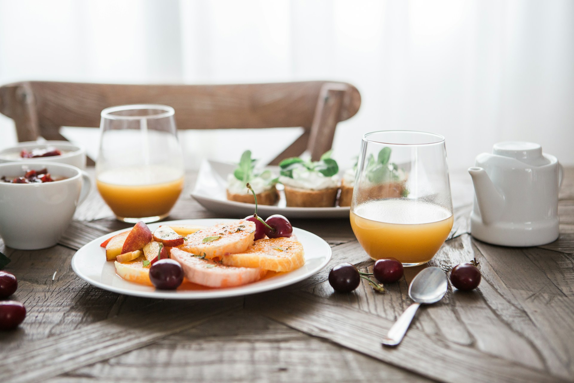 Healthy prenatal breakfast with fresh fruit, whole-grain toast, and orange juice on a wooden table, promoting pregnancy nutrition and balanced eating for maternal health.