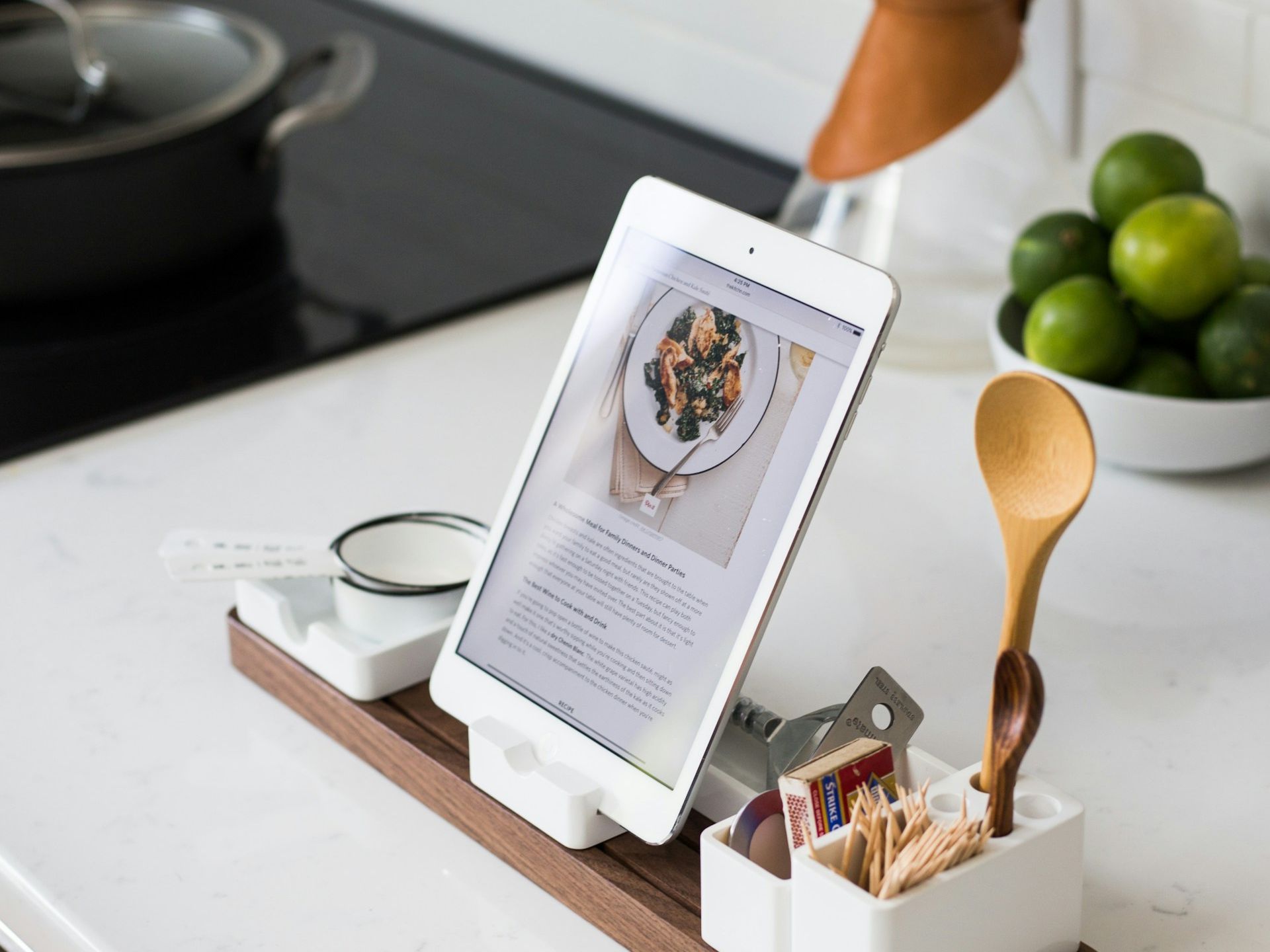 Tablet displaying a healthy plant-based recipe in a modern kitchen setting with fresh limes and cooking utensils.