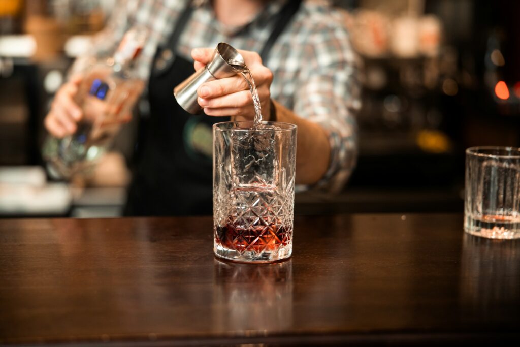 Person pouring alcohol into a glass, symbolizing habits that negatively impact gut health.